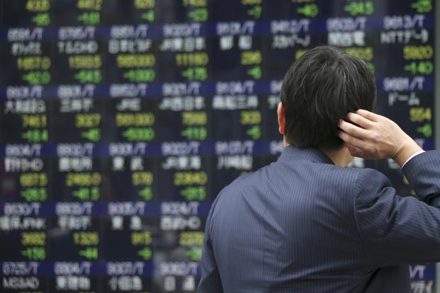 A man looks at an electronic board of a securities firm in Tokyo ahead of the US Federal Reserve’s decision to hike interest rate