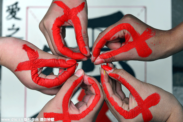 Volunteers in a university in Liaocheng city East China's Shandong province painted red ribbons on the sides of their hands during an awareness campaign to mark World AIDS Day which aims to raise public awareness and support for HIV  AIDS patients