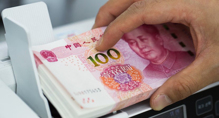 An employee places Chinese one-hundred yuan banknotes into a counting machine at the Counterfeit Notes Response Center of KEB Hana Bank in Seoul South Korea. The offshore yuan climbed the most in a week on optimism that China's leaders are focusing on