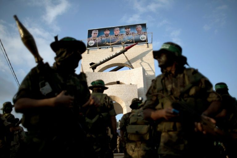 Members of the al Qassam Brigades the armed wing of Hamas stand with a model of a Qassam rocket