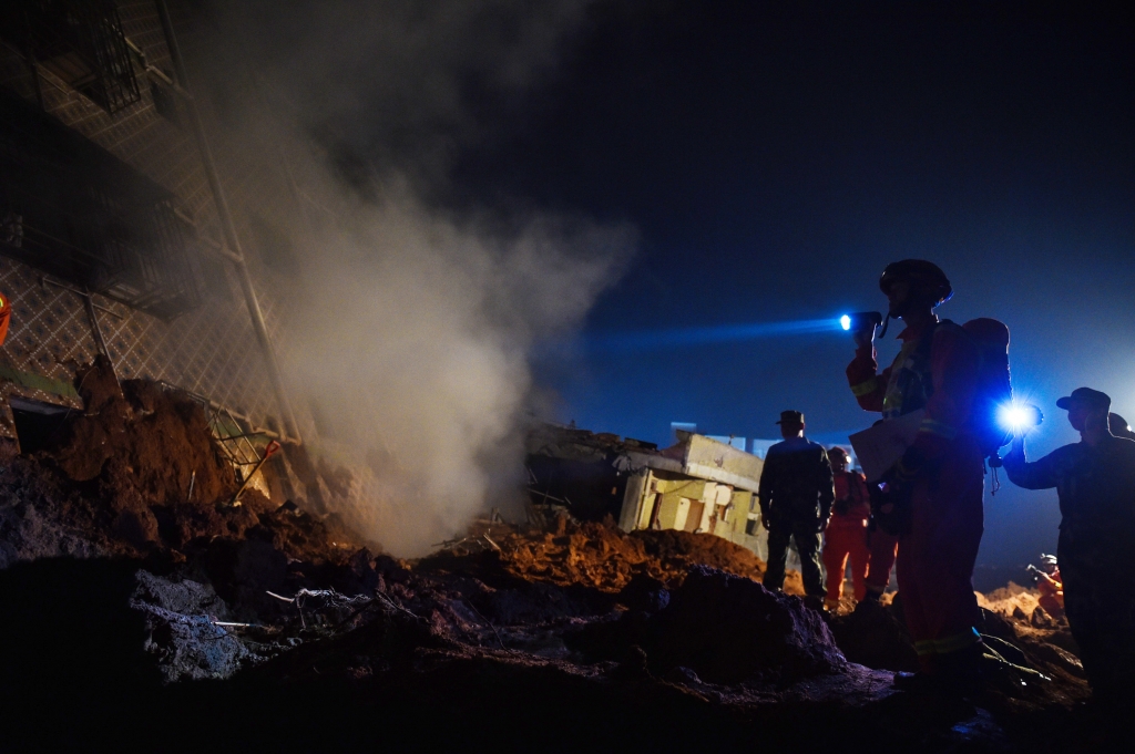 Rescuers search for trapped people at a residential building in Shenzhen south China's Guangdong Province on Sunday. Three people were injured and 27 remain missing after a landslide buried 22 residential and industrial buildings. Mai Siqian /Xinhua