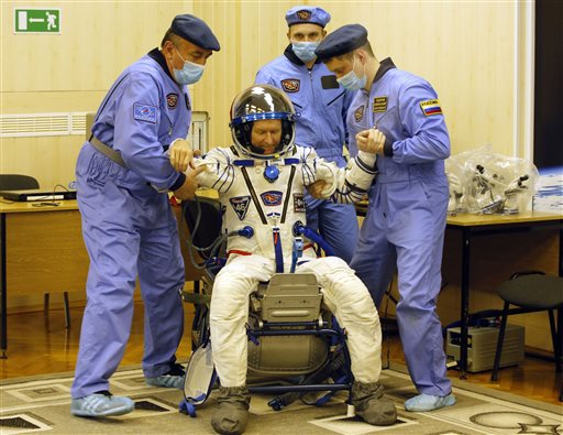 Russian Space Agency experts help British astronaut Tim Peake a member of the main crew to the International Space Station, to stand up after inspecting his space suit prior to the launch of Soyuz-FG rocket at the Russian leased Baikonur cosmodrome