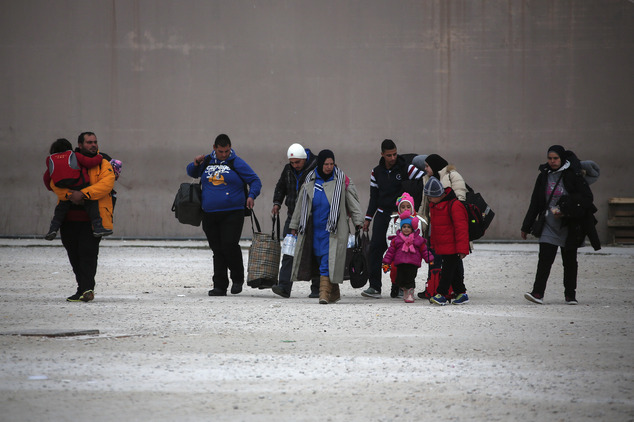 Migrants carry their belongings as they leave a former Olympic indoor stadium where they had been housed in Faliro southern Athens on Wednesday Dec. 16 2