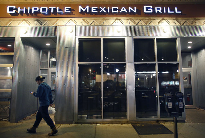 A man walks near a closed Chipotle restaurant on Monday Dec. 7 2015 in the Cleveland Circle neighborhood of Boston. Chipotle said late Monday that it closed the restaurant after several students at Boston College including members of the men ™s bas