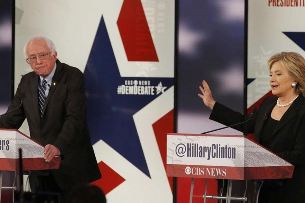 Democratic US presidential candidate former US Secretary of State Hillary Clinton speaks as fellow candidate and Senator Bernie Sanders listens