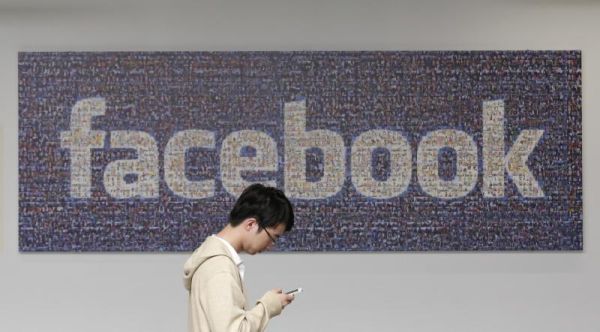 A man walks past a Facebook sign