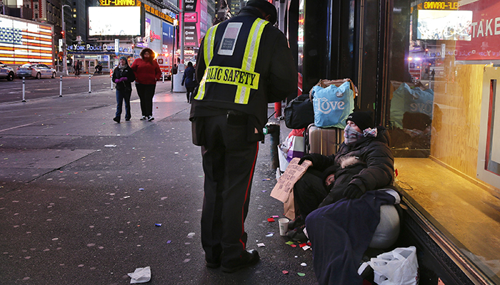 A public safety officer talks to a homeless couple in New York's Times Square