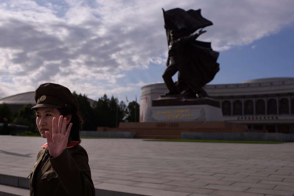 A uniformed tour guide gestures to tourists outside the War Museum in Pyongyang. U.S. citizens can visit North Korea as tourists