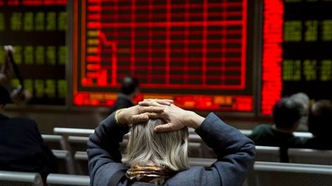 A woman reacts near a display board showing the plunge in the Shanghai Composite Index at a brokerage in Beijing China