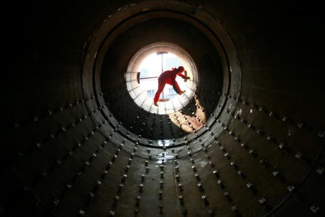 A worker checks steel pipes at an oil field preparing for oil and gas exploitation in Yilong Sichuan province