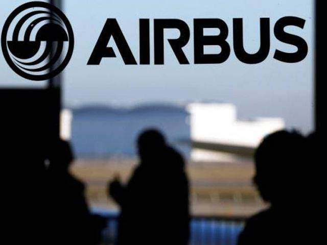 People are silhouetted past a logo of the Airbus Group during the Airbus annual news conference in Colomiers near Toulouse