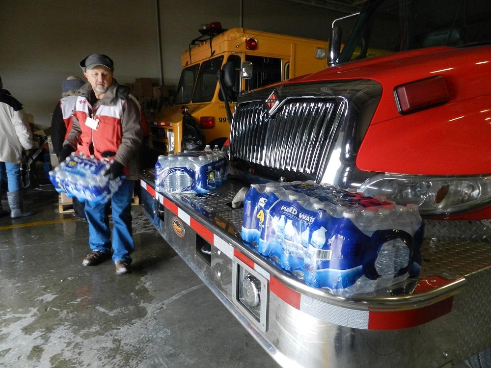 An American Red Cross volunteer stacks cases of bottled water at Flint fire station #3