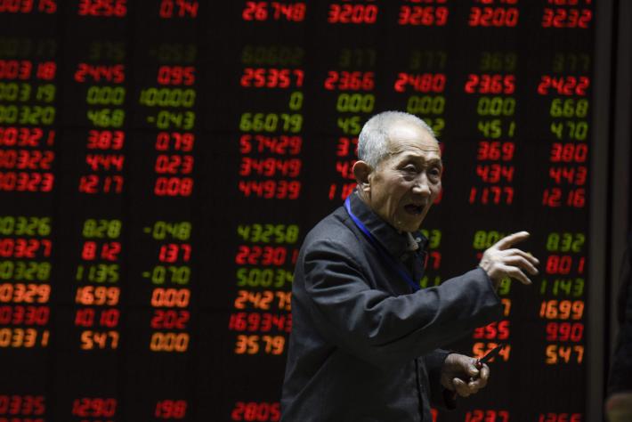 An investor gestures in front of an electronic board showing stock information at a brokerage house in Beijing yesterday. AFP