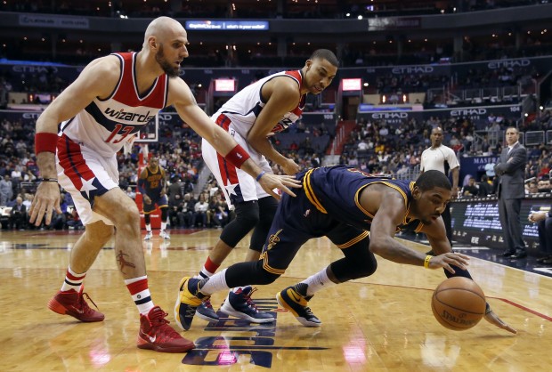 Cleveland Cavaliers guard Kyrie Irving lunges for the ball with Washington Wizards center Marcin Gortat and forward Otto Porter Jr. behind him during the first half of an NBA basketball game Wednesday Jan. 6 2016 in Washington. (AP