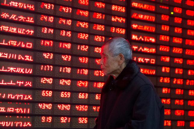 An investor walks past an electronic screen showing stock information at a brokerage house in Nanjing Jiangsu province