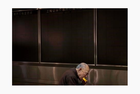 An investor eats near a darkened stock price display board after trading was halted at a brokerage in Beijing China Thursday Jan. 7 2016. China halted stock trading Thursday its second daylong trading suspension this week after prices plunged in the