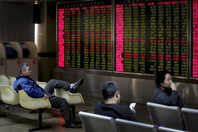 People sit in front of an electronic board displaying stock prices at a brokerage house in Beijing Thursday Jan. 14 2016. Asian stock markets sank across the board Thursday as pessimistic sentiment following sustained weakness in oil prices and a dive