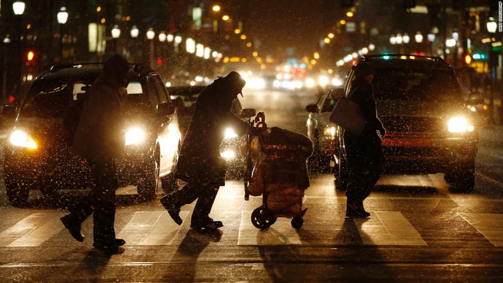 People walk across Market Street in Philadelphia as snow falls during the evening commute on Friday January 22. A monster storm is traveling north after lashing parts of the South and the Mid-Atlantic