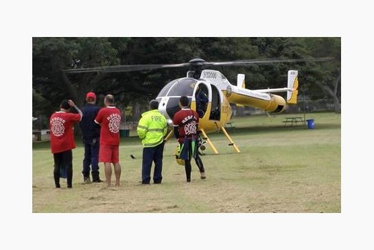 Fire Department rescue personnel stand near a department helicopter near the beach at Haleiwa Hawaii Friday Jan. 15 2016. Two Marine helicopters carrying 12 crew members collided off the island of Oahu during a nighttime training mission and rescuers