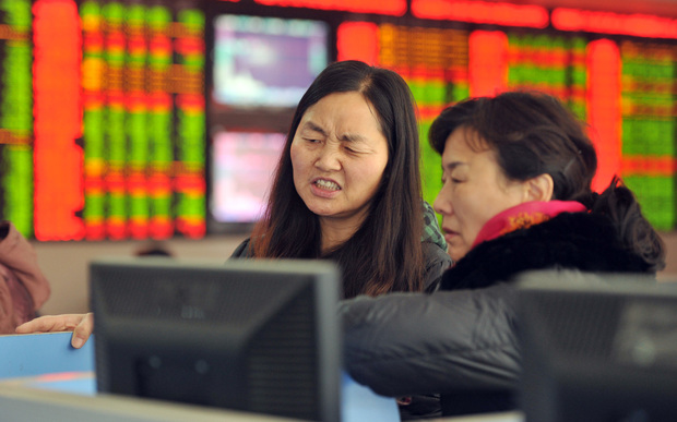 Concerned Chinese investors look at prices of shares at a stock brokerage house