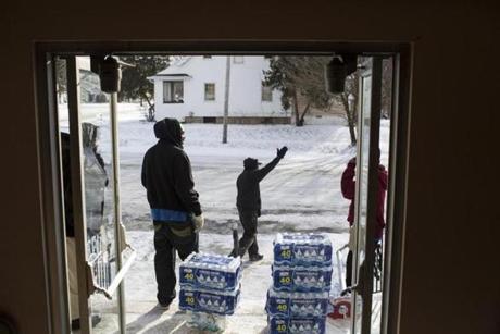 Aaron Dunigan waved to cars as volunteers handed out water Monday in Flint Mich