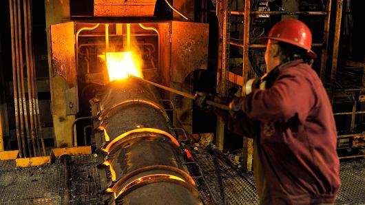 A worker uses a rod at a furnace containing molten liquid copper at the RTB Bor Group copper mining and smelting plant in Bor Serbia