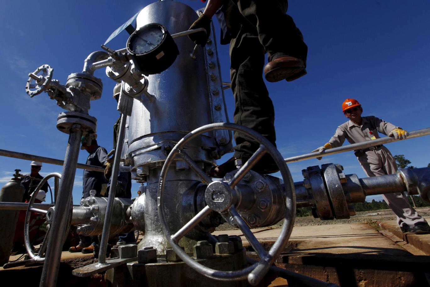 A worker climbs on a gauge at a crude oil well