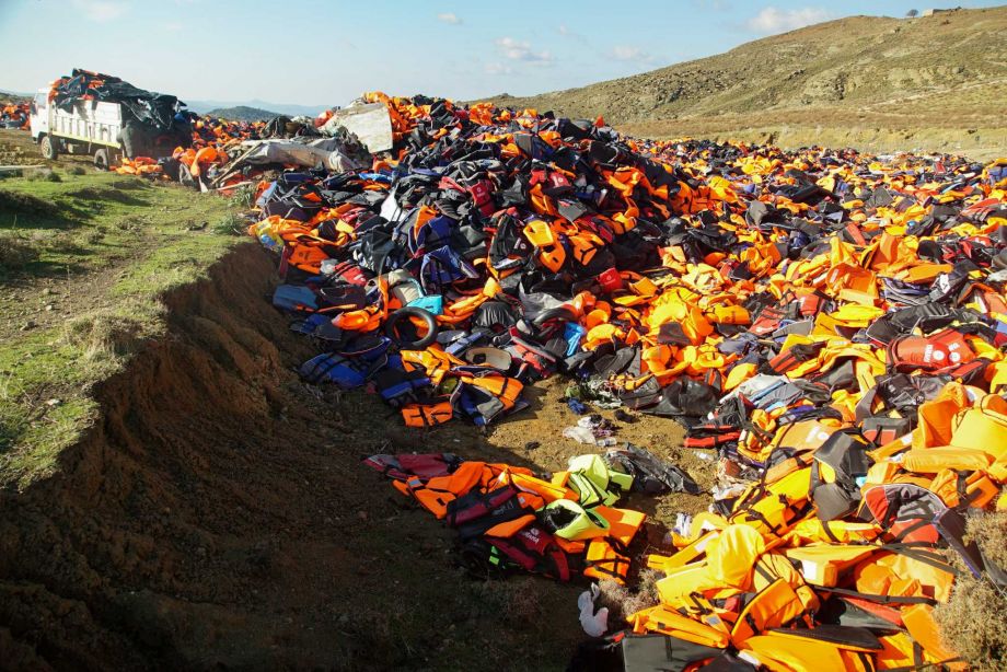 A Man unloads a truck filled with various life Jackets at the garbage area in the mountains of Lesbos Island Greece Monday Jan. 25 2016. The buoyancy aides are discarded by migrants and collected from along the shore-line of the Greek island. More