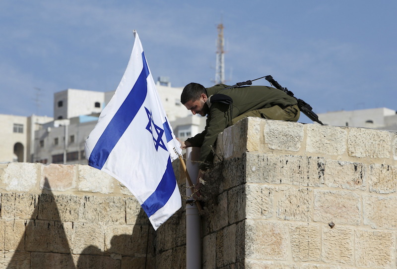 An Israeli soldier removes the Israeli flag from a house as Israeli troops forcibly remove Jewish settlers from homes in the West Bank city of Hebr