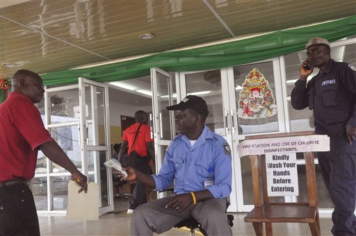 A health worker takes a man's temperature center before his is allowed to enter into a government building with a message right reading'Kindly wash your hands before entering the building in Monrovia Liberia Thursday Jan. 14 2016. The World H