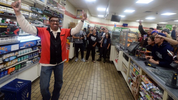 7-Eleven store clerk M Faroqui celebrates after learning the store sold a winning Powerball ticket