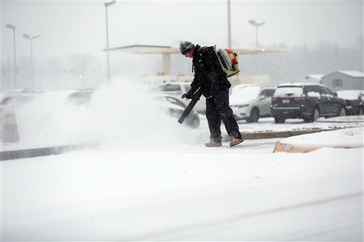 George Morris with Standard Parking works on clearing an entrance to airport parking as snow falls Friday morning Jan. 22 2016 in Roanoke Va. Airlines have canceled more than 2,700 flights Friday to from or within the U.S. as a blizzard swings