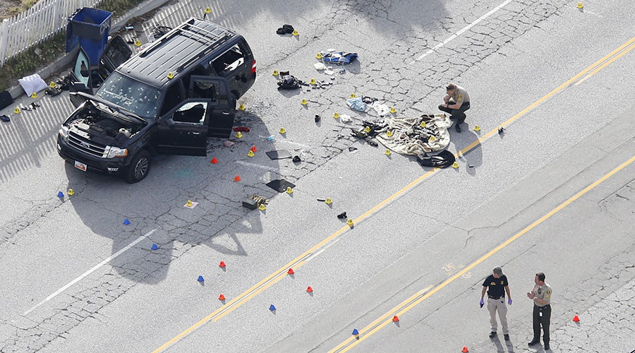 Law enforcement officers look over the evidence near the remains of a SUV involved in the Wednesdays attack is shown in San Bernardino California