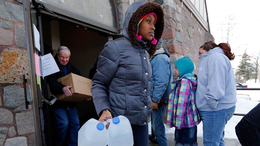 Genetha Campbell carries free water being distributed at the Lincoln Park United Methodist Church in Flint Mich