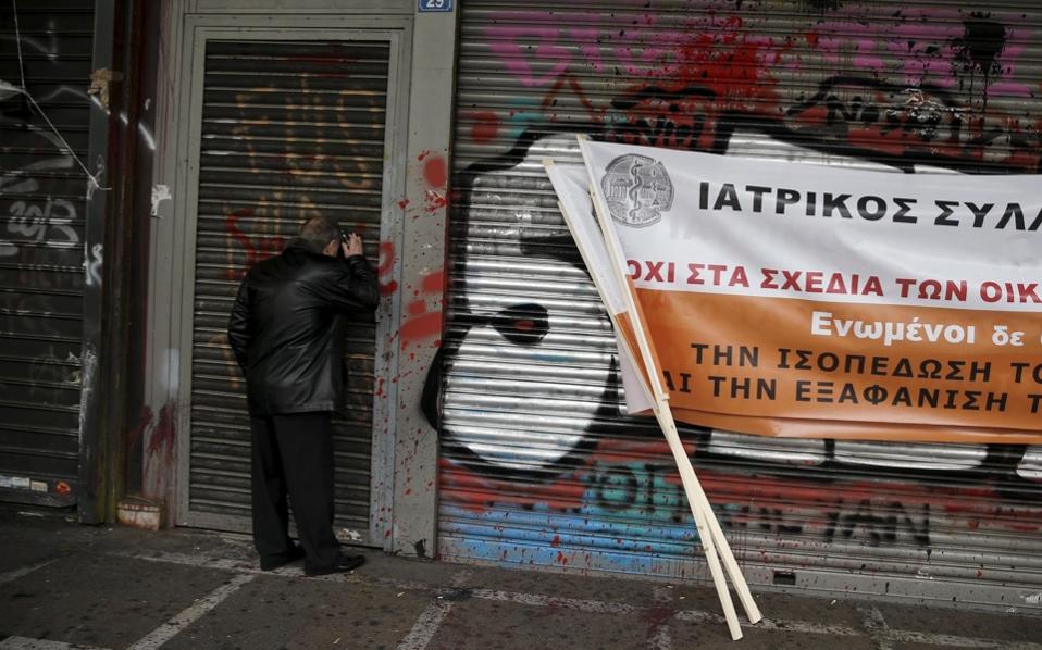 A protester looks through the closed entrance of the Labor ministry during a protest of Greek doctors against planned pension reforms in Athens on Monday