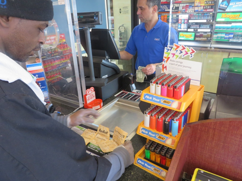 A customer at a Mobil station in Walker's Point buys a Powerball ticket Tuesday. Milwaukee area service stations have been swarmed by lottery players hoping to win the record $1.4 billion jackpot