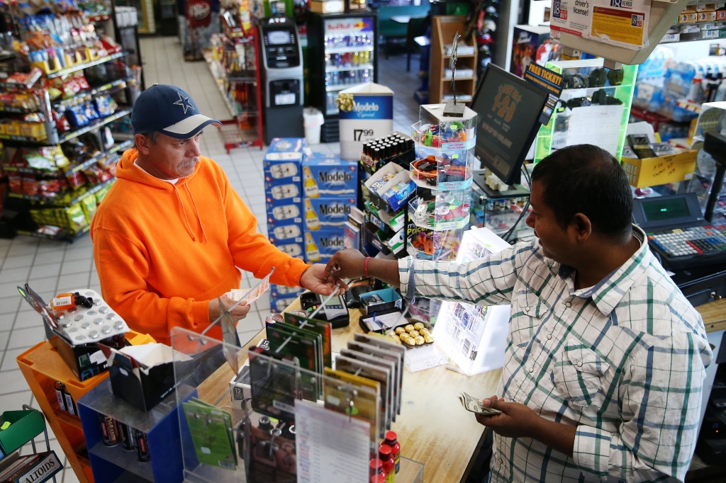 Clerk Shashwat Mali sells a Powerball ticket to Pedro Armendariz of Caddo Mills Texas at the Appletree Food Mart in Princeton Texas Monday