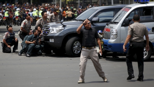 Police officers react near the site of a blast in Jakarta Indonesia early Thursday. Several explosions went off and gunfire broke out in the centre of the Indonesian capital