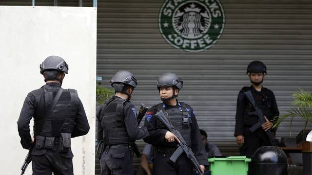 Indonesian police officers on guard near the Starbucks cafe where the attack took place