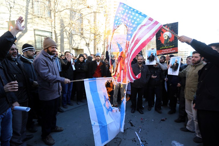 Iranian men burn Israeli and American flags during a demonstration against the execution of prominent Shiite Muslim cleric Nimr al Nimr by Saudi authorities