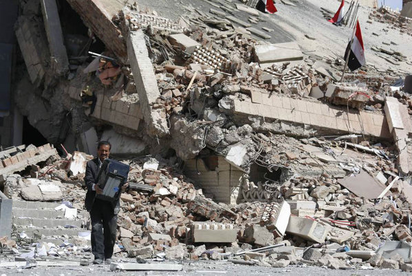 An employee carries a printer out of the Chamber of Trade and Industry headquarters after it was hit by a Saudi-led airstrike in Sanaa Yemen Tuesday Jan. 5 2016