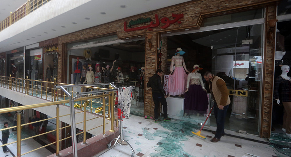 Iraqi men clean up the damage at the al Jawaher mall in eastern Baghdad the day after a bomb attack