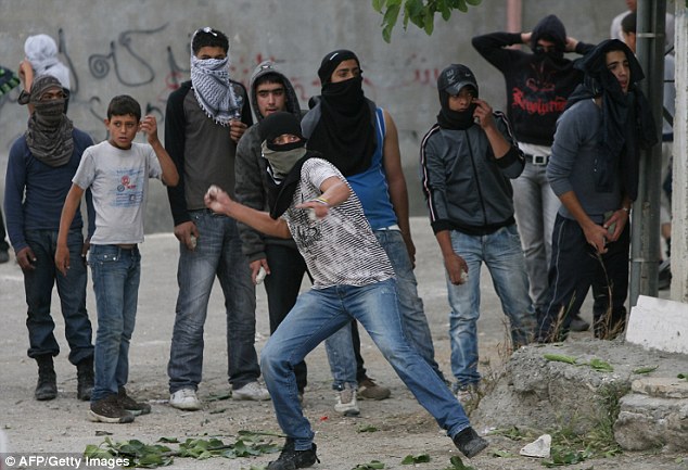 Palestinian youths throw stones at Israeli soldiers during confrontations in the restive West Bank city of Hebron