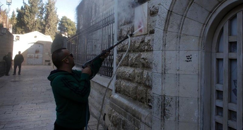 A Jerusalem municipality worker cleans anti Christian graffiti in Hebrew daubed on the Church of the Dormition one of Jerusalem's leading pilgrimage sites outside of the Old City of Jerusalem