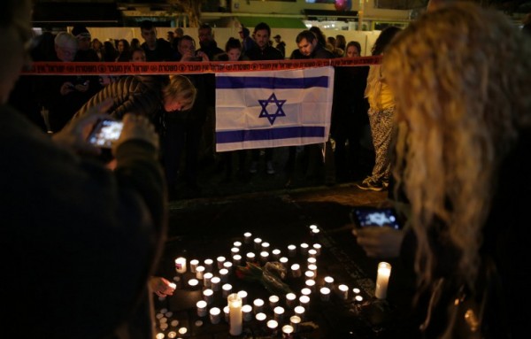 Israelis attend a candle vigil at the site of a shooting at a pub in Tel Aviv killing two people and injuring seven others