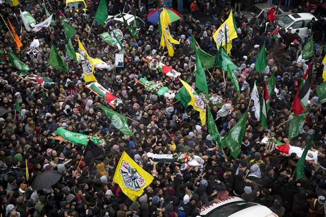 Palestinian mourners carry the bodies of 17 Palestinians during their mass funeral in the West Bank city of Hebron Saturday Jan. 2 2016. The Israeli military has transferred almost two dozen bodies of Palestinians it says were involved in violence over