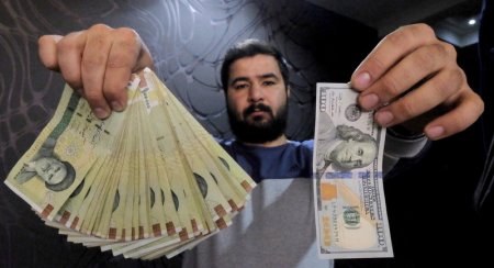 A money changer poses for the camera with a U.S dollar and the amount being given when converting it into Iranian rials, at a currency exchange shop in Tehran's business district Iran