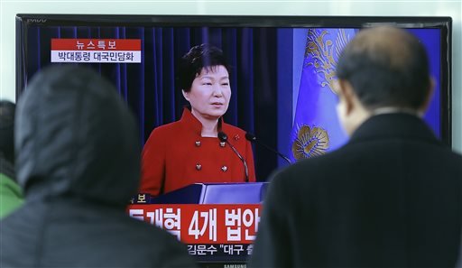 People watch a TV screen showing the live broadcast of South Korean President Park Geun-hye's press conference at the Seoul Railway Station in Seoul South Korea Wednesday Jan. 13 2016. President Park on Wednesday called for Chinese help to launch wha