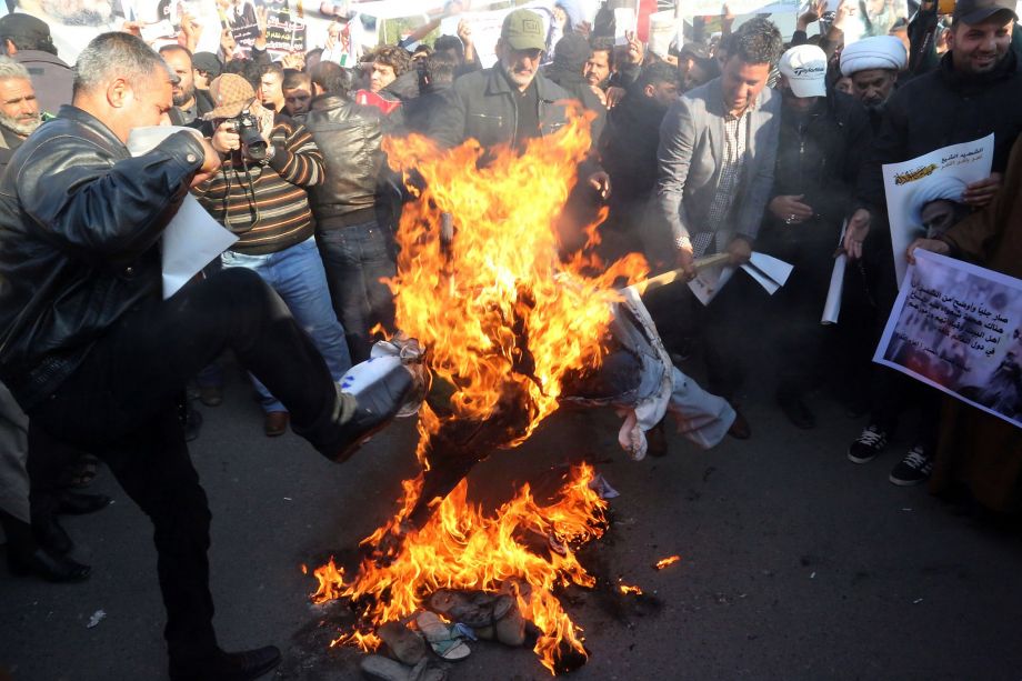 Followers of Shiite cleric Muqtada al Sadr burn an effigy of King Salman of Saudi Arabia as they hold posters of Sheik Nimr al Nimr during a demonstration in Baghdad Iraq Monday Jan. 4 2016. Demonstrations are also being called for in the predominantl