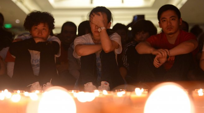 Chinese relatives of passengers on the missing Malaysia Airlines flight MH370 pray by candles at the Metro Park Hotel in Beijing